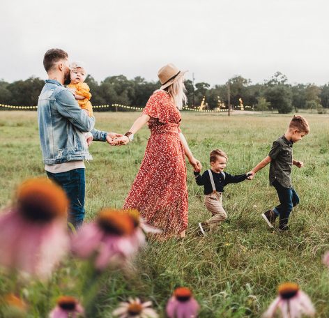 Familie på vej gennem en blomstereng i naturen